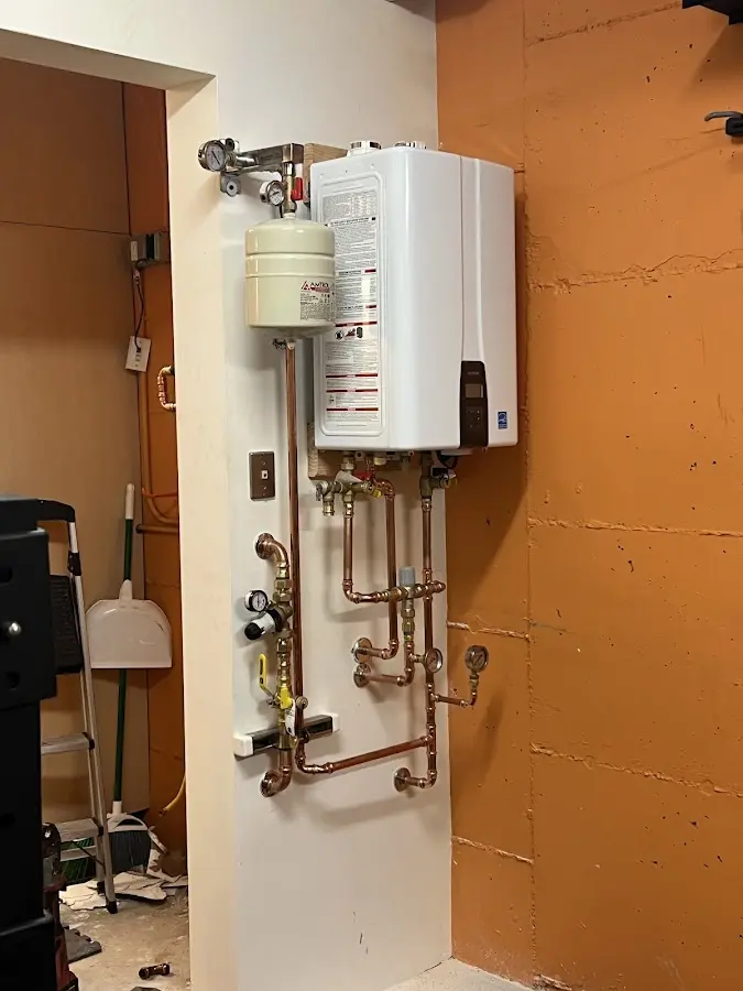 Plumbing technician inspecting water heater connections in New Baden